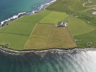 Oblique aerial view centered on the cropmarks of the infilled stream gullies and the remains of the brochs at Northfield, taken from the N.