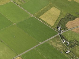 Oblique aerial view centered on the cropmarks of a barrow at Hall of Ireland with the farmstead and mill of Ireland adjacent, taken from the SE.