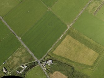 Oblique aerial view centered on the cropmarks of a barrow at Hall of Ireland with the farmstead and mill of Ireland adjacent, taken from the SSE.