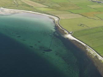 Oblique aerial view centered on the pier at Evie with St Nicholas' Chapel adjacent, taken from the N.