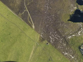 Oblique aerial view centred on the remains of the Castle Bloody chambered cairn, taken from the S.