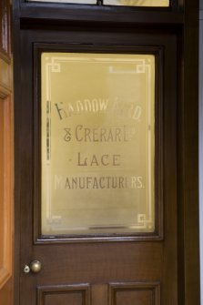 Interior. Ground floor, main office area, entrance, detail of etched glass panel on door with manufacturers name, 1923.