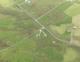 Oblique aerial view centred on the remains of the radar station buildings with the remains of the croft adajacent, taken from the NE.