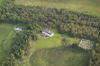 Oblique aerial view centred on the country house with the garage adjacent, taken from the NW.