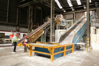 Interior. Building 1, Wood Pulp Storage showing Conveyors and Pulpers nos.1 (centre, behind Buffer Tank) and 3 (right). Control Room (grey wall) on 1st floor adjacent to Pulper no.1. Charles Whittaker (production manager) and Miriam McDonald (RCAHMS) to left of picture