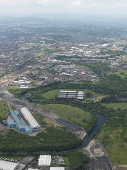 General oblique aerial view centred on the steel works with the motorway extension works adjacent, taken from the ENE.