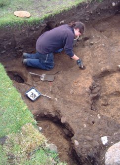 Sophie Laidler excavating the lower burnt mound deposits in Trench 14, from the NE