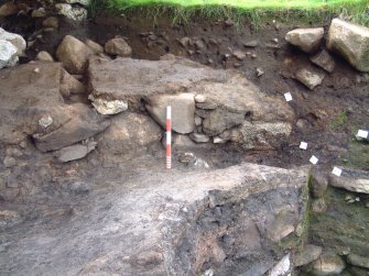 Trench 14 from the ENE showing partially incovered revetment wall F15.14 and exposed clay surface C15.34 (scale - 0.5m)