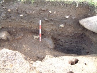 Trench 14 from the E showing natural karstic clay in foreground, edge of hearth setting F14.14 and deposits within pit-type feature (scale = 0.5m)