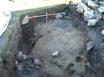 Trench 14 from the S showing S-facing baulk, natural karstic clay, revetment wall F14.12, hearth setting F14.14 and deposits falling away into pit feature (scales = 2m and 0.5m)
