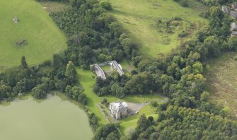 Oblique aerial view centred on the country house with the stable block adjacent, taken from the ESE.