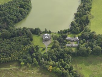 Oblique aerial view centred on the country house with the stable block adjacent, taken from the N.