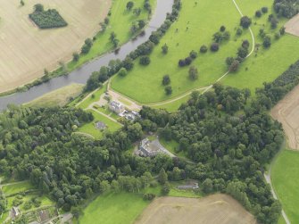 Oblique aerial view centred on the country house with the stable block adjacent , taken from the NE.