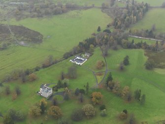 Oblique aerial view centred on the country house with the stables adjacent, taken from the SE.