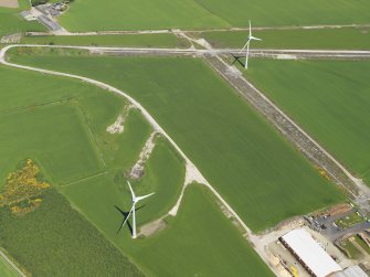 Oblique aerial view of two turbines of the Boyndie Windfarm Electricity Generating Station and the remains of the runways of Boyndie airfield, taken from the SSW.