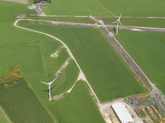 Oblique aerial view of two turbines of the Boyndie Windfarm Electricity Generating Station and the remains of the runways of Boyndie airfield, taken from the SSW.