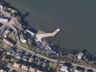 Oblique aerial view centred on the remains of the flying boat base with the harbour adjacent, taken from the SE.