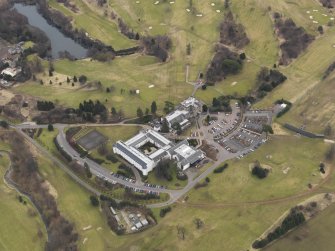 Oblique aerial view centred on the country house with the country club adjacent, taken from the NW.