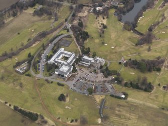 Oblique aerial view centred on the country house with the country club adjacent, taken from the SW.
