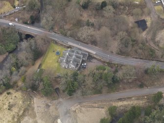 Oblique aerial view centred on the house with the road bridge adjacent, taken from the SE.