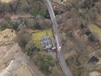 Oblique aerial view centred on the house with the road bridge adjacent, taken from the NE.