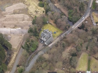 Oblique aerial view centred on the house with the road bridge adjacent, taken from the N.