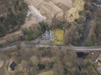 Oblique aerial view centred on the house with the road bridge adjacent, taken from the NNW.