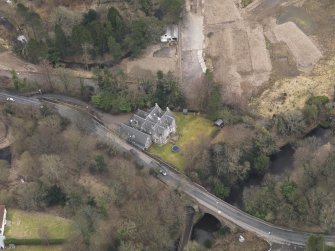 Oblique aerial view centred on the house with the road bridge adjacent, taken from the NW.