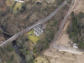 Oblique aerial view centred on the house with the road bridge adjacent, taken from the SSW.