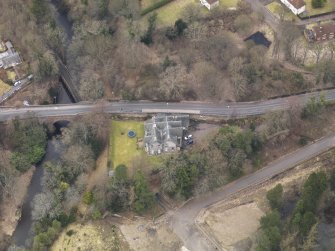 Oblique aerial view centred on the house with the road bridge adjacent, taken from the SSE.