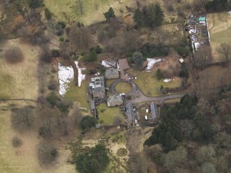 Oblique aerial view centred on the country house with the stable block, taken from the NE.