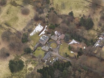 Oblique aerial view centred on the country house with the stable block, taken from the NNE.