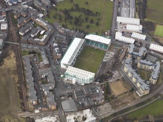 Oblique aerial view centred on the stadium with the half demolished E stand adjacent, taken from the SE.