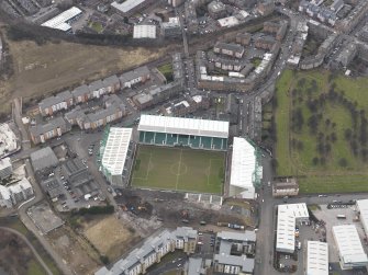 Oblique aerial view centred on the stadium with the half demolished E stand adjacent, taken from the NE.