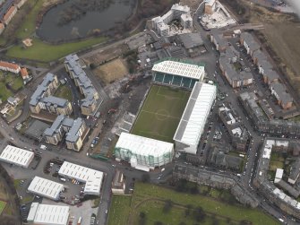 Oblique aerial view centred on the stadium with the half demolished E stand adjacent, taken from the NNW.