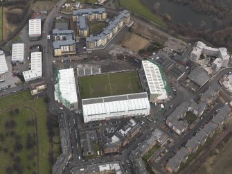 Oblique aerial view centred on the stadium with the half demolished E stand adjacent, taken from the SW.