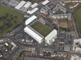 Oblique aerial view centred on the stadium with the half demolished E stand adjacent, taken from the SW.