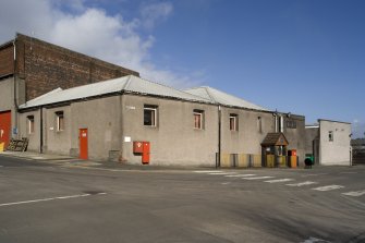 Canteen, 84 Vintner Street (elevation onto Harvey Street), view from SW. The building behind retains some earlier brickwork dating from between 1867 and 1896 (building footprint does not exist before 1867 according to the Ordnance Survey map). Both these buildings are harled obscuring the age of the structures. Note the blocked cart entrance to the left of the bright red door.