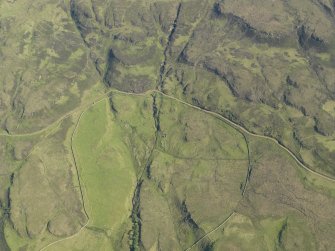 Oblique aerial view of the remains of the township buildings at Portnabhata with the road running past, taken from the NNW.