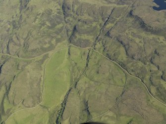 Oblique aerial view of the remains of the township buildings at Portnabhata with the road running past, taken from the NW.