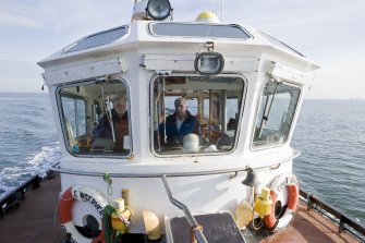 En route to the island, view of bridge with boat owner Bill Simpson and RCAHMS field surveyor David Easton.