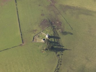 Oblique aerial view centred on the ruins of the tower house with the chapel and the graveyard adjacent, taken from the NE.