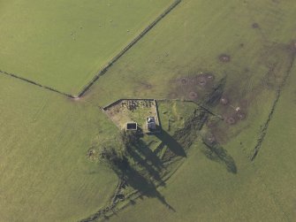 Oblique aerial view centred on the ruins of the tower house with the chapel and the graveyard adjacent, taken from the NNW.