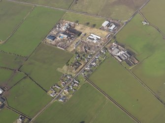 Oblique aerial view centred on the village with the airfield domestic site adjacent, taken from the SE