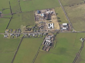 Oblique aerial view centred on the village with the airfield domestic site adjacent, taken from the NE.