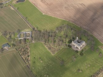 Oblique aerial view centred on the country house with the Home Farm adjacent,  taken from the SSW.