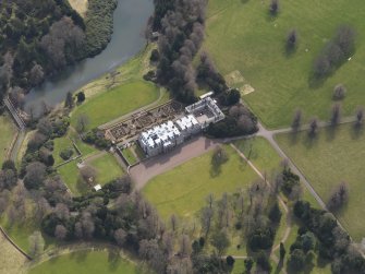 Oblique aerial view centred on the country house with the formal garden adjacent, taken from the N.