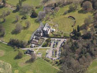 Oblique aerial view centred on the hotel with the stable block adjacent, taken from the W.