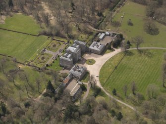 Oblique aerial view centred on the country house with the stable block adjacent, taken from the NNE.