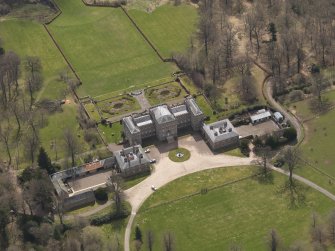 Oblique aerial view centred on the country house with the stable block adjacent, taken from the N.